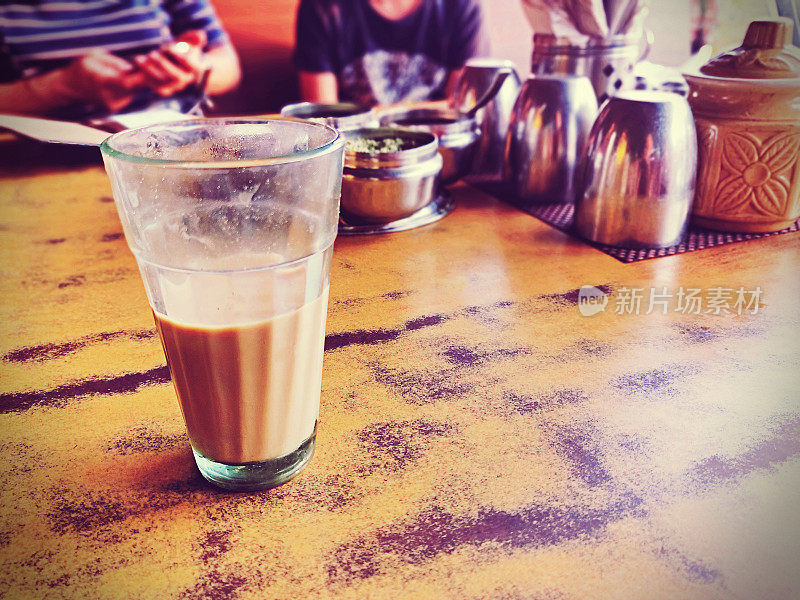 一杯印度混合茶(Masala Chai，印度混合茶)放在有划痕的木制桌面上。景深